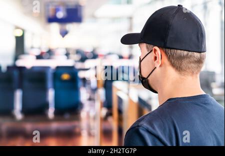 Maske am Flughafen. Mann, der im Terminal auf den Flug wartet. Corona-Virus, covid19 und Reise. Tourist trägt Gesichtsmask während einer Pandemie am Gate. Stockfoto
