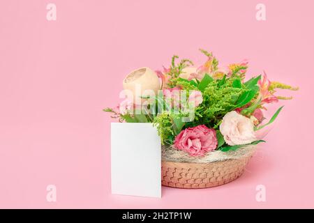 Frischer schöner Blumenstrauß mit rosa Blumen auf pastellrosa Hintergrund mit weißer leerer Karte, Mockup, Kopierraum Stockfoto