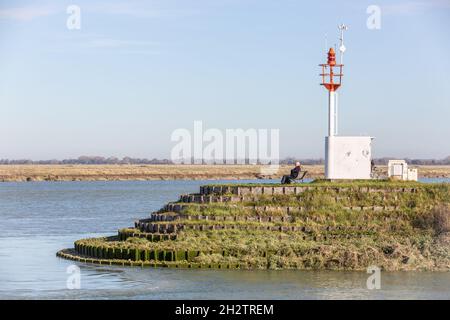 Leuchtfeuer, das den Zugang zum Hafen von Saint-Valery markiert, Mann, der auf einer Bank sitzt. Baie de Somme. Frankreich Stockfoto