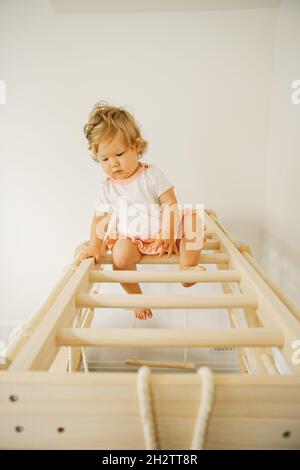 Babymädchen spielen mit Entwicklungsstruktur aus Holz zu Hause oder im Kindergarten oder in der Kindertagesstätte Stockfoto
