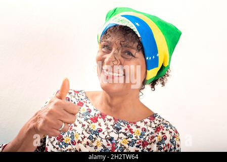 Porträt einer reifen, lächelnden brasilianischen Frau, die eine Bandana mit der Nationalflagge trägt Stockfoto