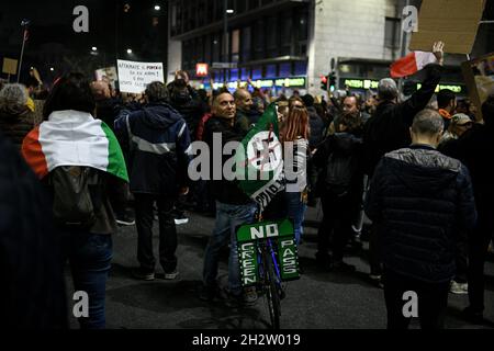 Mailand, Italien - 23. Oktober 2021: Ein Mann fährt mit dem Fahrrad mit einem „No Green Pass“-Schild, während sich Menschen versammeln, um gegen den Grünen Pass zu protestieren, der für alle öffentlichen und privaten Arbeiter obligatorisch ist Stockfoto