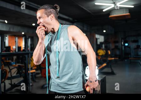 Junge gutaussehende Sportler hungrig und essen gesunde Apfelfrüchte im Fitnessstudio Stockfoto