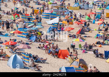 Fistral Beach in Newquay in Cornwall. Urlaubsreisende drängen sich zum Fistral Beach, um die intensive Sommersonne zu genießen. Stockfoto