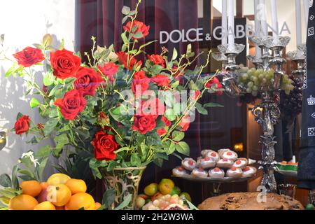 Mailand, Italien - 16. Dezember 2019: Wunderschöne Schaufensterdekoration der Boutique Dolce & Gabbana in Mailand mit rotem Rosenstrauß, sizilianischem Gebäck. Stockfoto