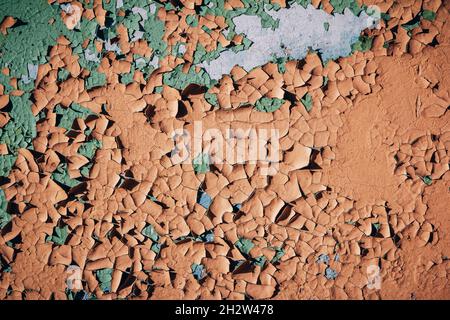 Grunge Hintergrund – Gebäudewand mit abblätternder orange, grün und blauer Farbe. Bunte, rissige Textur Stockfoto