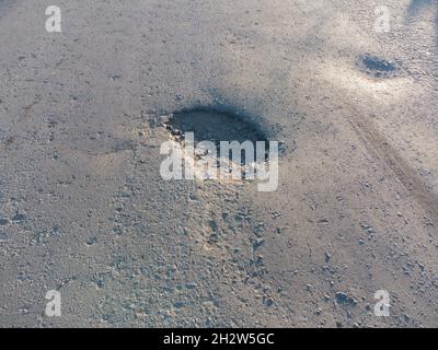 Nahaufnahme einer Grube am Damm. Beschädigte Straße Stockfoto