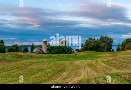 Morgenansicht eines Silos und einer Scheune am Lake Champlain in North Hero, Vermont mit Blick auf die Adirondack Mountains in New York über den See. Stockfoto