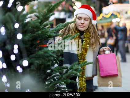 Mädchen in gestrickten Hut Wahl Weihnachtsbaum Stockfoto
