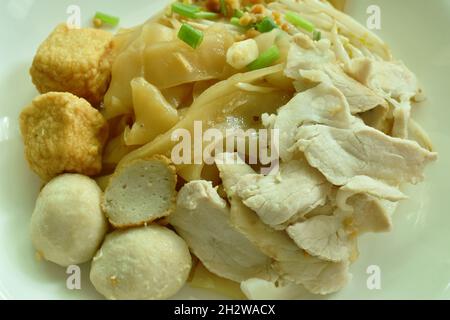 Trockene große Reisnudeln Dressing schwarzen süßen Sojabohnensauce Belag in Scheiben gekochtes Schweinefleisch und Ball auf dem Teller Stockfoto