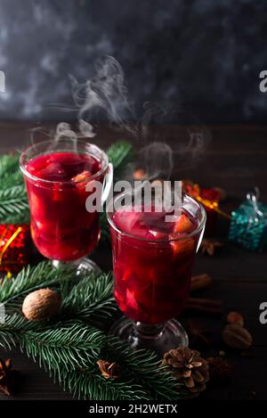 Zwei Gläser mit Glühwein auf weihnachtlichem Hintergrund auf dunklem Holzgrund Stockfoto