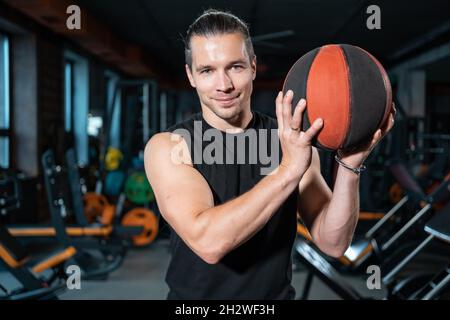 Junger Athlet männlich mit Basketball oder Medizinball hat Training im Fitnessstudio Stockfoto