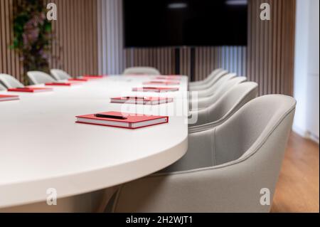 Leerer Tagungsraum und Konferenztisch. Rote Tagebücher auf dem Tisch vor einem Geschäftstreffen Stockfoto