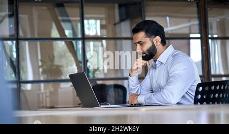 Indischer Geschäftsmann mit Laptop-Computer im Büro mit Blick auf Laptop. Stockfoto