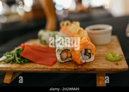 Sushi mit Essstäbchen essen. Sushi Roll japanisches Essen im Restaurant. Kalifornisches Sushi-Rollset mit Lachs, Gemüse, fliegendem Fischrogen und Kaviar Stockfoto