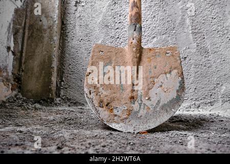 Bauarbeiten der Verputzung. Foto aufgenommen Niederwinkelschaufel vor der kürzlich aus Beton geputzten Wand. Stockfoto