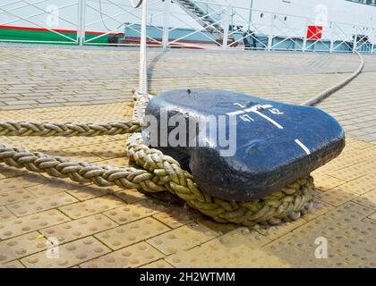 Eine einzige Anlegevorrichtung mit gewickelten Seilen hält das Schiff auf dem Dock. Nahaufnahme Stockfoto