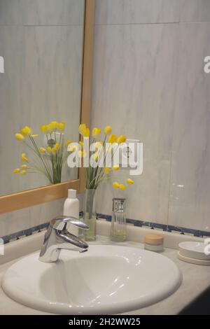 Panorama-Waschbecken im Badezimmer, minimalistisch mit gelben Blumen, köln und männlichen Kosmetikprodukten für Hygiene und Behandlung eingerichtet. Beauty Home Stockfoto