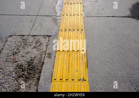 Gelbe Straßenabdeckungen, um Blinde beim Gehen zu orientieren. Stockfoto