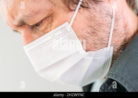 Kaukasischer Mann, der eine schützende Atemschutzmaske trägt, um sich vor einer Covid-19-Infektion zu schützen, selektiver Fokus Stockfoto