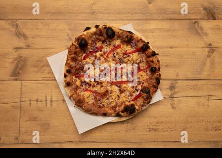 Mexikanische Pizza mit roten Zwiebeln, geschmolzenem Cheddar-Käse, Paprikastreifen auf Holztisch Stockfoto