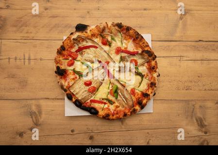 Gartenpizza mit in Scheiben geschnittenen Auberginen mit Zucchini-Scheiben, Paprikastreifen, weißen Zwiebeln, Kirschtomaten und Mozzarella-Käse Stockfoto