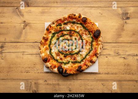 Pizza mit karamellisierten Zwiebeln mit Mozzarella-Käse und Pesto-Sauce auf weißem Backpapier Stockfoto