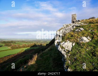 Brent Tor wird von der Kirche St. Michael de Rupe in der Nähe von Tavistock in Devon, Großbritannien, gekrönt und wirft im frühen Morgenlicht einen Schatten über die Landschaft Stockfoto