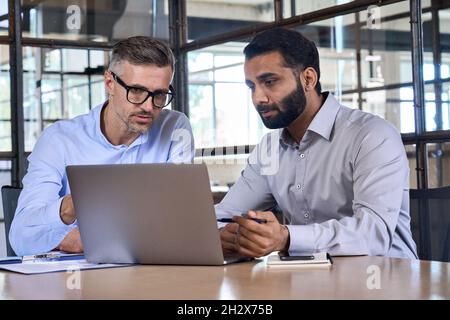 Zwei Analysten diskutieren über Datenverwaltung mit einem Laptop. Stockfoto