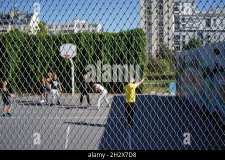 Kinder spielen Basketball auf einem geschlossenen Platz, Sport im Jardins d’Éole, 20 Rue du Département, 75018 Paris, Frankreich Stockfoto