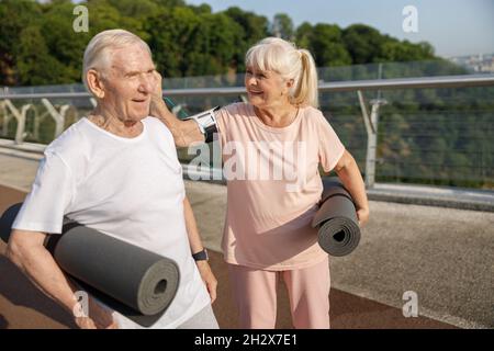 Die reife Frau legt das Ohrpolster in das Partnerohr, um auf dem Steg trainieren zu können Stockfoto