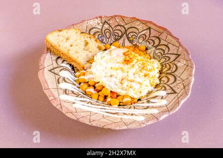 Teller mit gekochten Hülsenfrüchten mit Spiegelei darauf, garniert mit Olivenöl und Paprika de la Vera Stockfoto