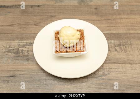 Süßes Mais-Popcorn-Dessert mit Keksstücken und Vanilleeis-Kugel auf weißem Geschirr Stockfoto