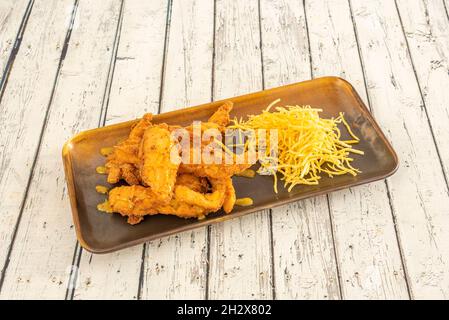 Knusprige Hähnchenstreifen in Eierteig und Pfannenrallado mit einer Sauce aus dem Jahr und Strohkartoffeln auf einem weißen Holztisch Stockfoto