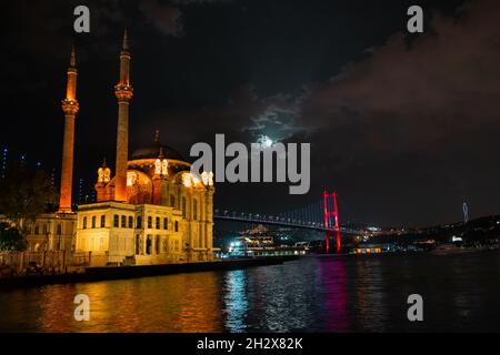 Ortaköy Moschee und Bosporus Brücke während der blauen Stunde, Vollmond und blauen Nachthimmel. Einer der beliebtesten Orte am Bosporus, Istanbul. Stockfoto