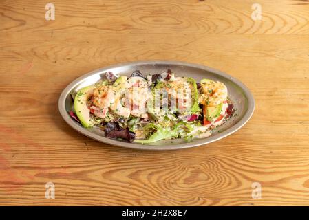 Metallblech mit Avocado und Garnelencocktail mit Salat und Tomate mit Petersilie und Sauce Stockfoto