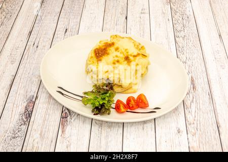 Pfannkuchen gefüllt mit Lachs und Kartoffeln, gekrönt mit geschmolzenem Käsegratin, Kirschtomaten und Salat mit einem Hauch von Balsamico-Essig Stockfoto