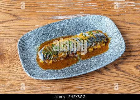 Makreleneintopf mit Gemüse und Sauce auf blauem Teller Stockfoto