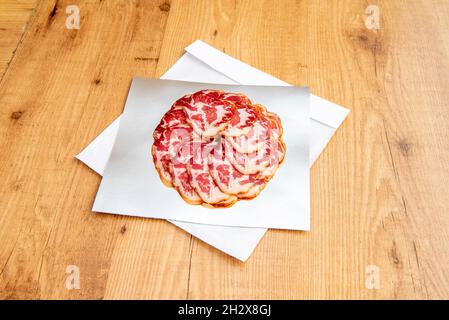 Frisch geschnittene, iberische Kotelett-Aufschnitt mit marmoriertem Speck auf metallischem Takeaway-Papier Stockfoto