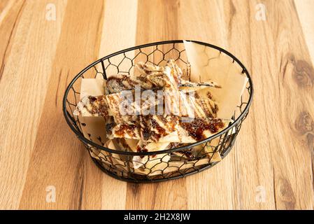 Gebratene Aubergine-Chips mit Rohrzucker-Sirup in einem schwarzen Metallkorb Stockfoto