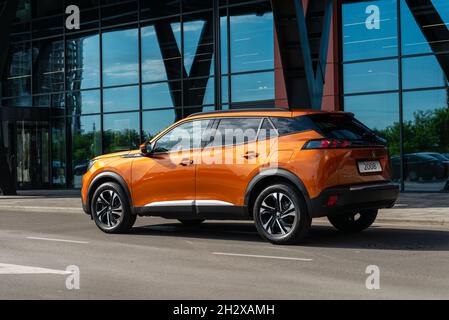 Kiew, Ukraine - 12. Juni 2021: Neuer orangefarbener Peugeot 2008 vor Glaswand Stockfoto