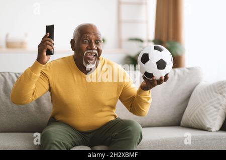 Reifer schwarzer Mann beim Sport im Fernsehen feiert Sieg im Freien Stockfoto