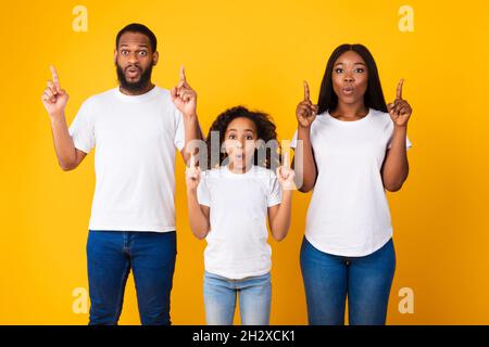 Überraschte schwarze Familie, die auf freien Platz im Studio zeigte Stockfoto