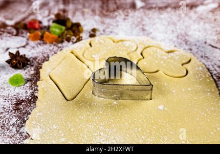 Backkulisse mit herzförmigem Keksschneider, gerolltem Gebäck, Weizenmehl, kandierten Früchten, Puderzucker und japanischem Sternanise. Hausgemachte Kekse für V Stockfoto