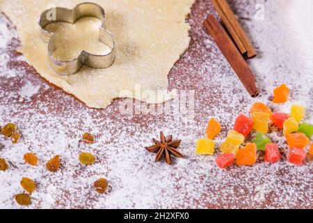 Backkulisse mit blumenförmigem Keksschneider, gerolltem Gebäck, Weizenmehl, kandierten Früchten, Puderzucker und japanischem Sternanise. Hausgemachte Kekse Stockfoto