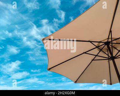 Sonnenschirm oder Sonnenschirm auf der Terrasse gegen den blauen Himmel mit einigen weißen Wolken, sonniger Tag Stockfoto