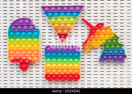 Draufsicht auf bunte Pop IT Fidget Spielzeuge auf weißer Kunststoffoberfläche platziert Stockfoto