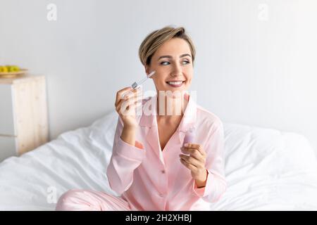 Porträt einer lächelnden Frau, die eine Flasche Serum hält Stockfoto