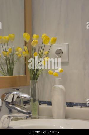 Waschbecken im Badezimmer, minimalistisch eingerichtet mit gelben Blumen, köln und männlichen Kosmetikprodukten für Hygiene und Behandlung. Beauty Home Spa-Konzept Stockfoto