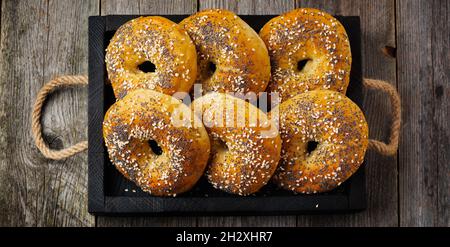Bagels in einer alten Keramikschale mit einer textilen Serviette auf einem hellen Stein- oder Betongrund. Selektiver Fokus. Draufsicht. Speicherplatz kopieren. Quadratisches Bild. Stockfoto